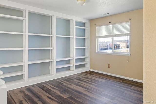 empty room with a textured ceiling and dark hardwood / wood-style floors