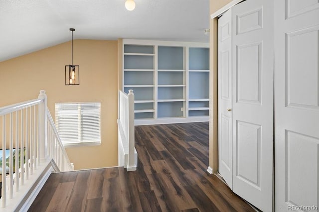 hallway featuring dark wood-type flooring and vaulted ceiling