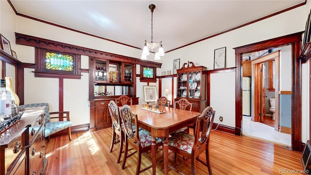 dining room with light hardwood / wood-style floors, crown molding, and a chandelier