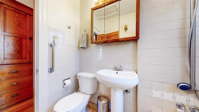 bathroom with backsplash, sink, toilet, and tile walls