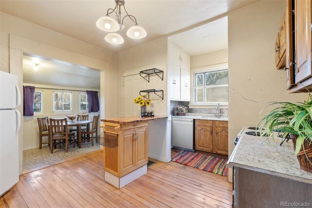 kitchen with a wealth of natural light, dishwasher, white fridge, and light wood-type flooring