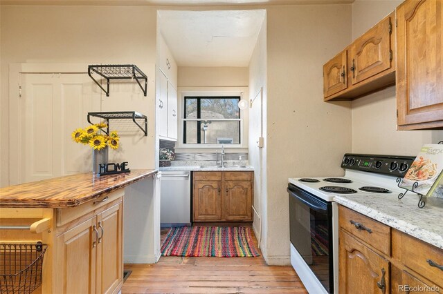 kitchen featuring sink, light stone counters, stainless steel dishwasher, white range with electric stovetop, and light wood-type flooring