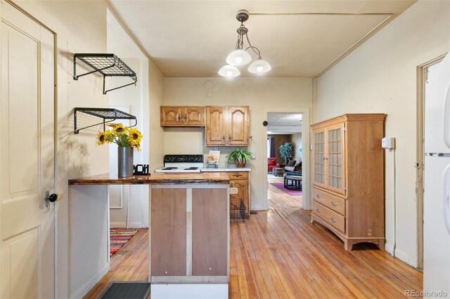 kitchen featuring decorative light fixtures, an inviting chandelier, light hardwood / wood-style floors, and white gas stove