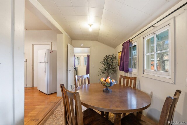 dining space with light hardwood / wood-style floors and vaulted ceiling