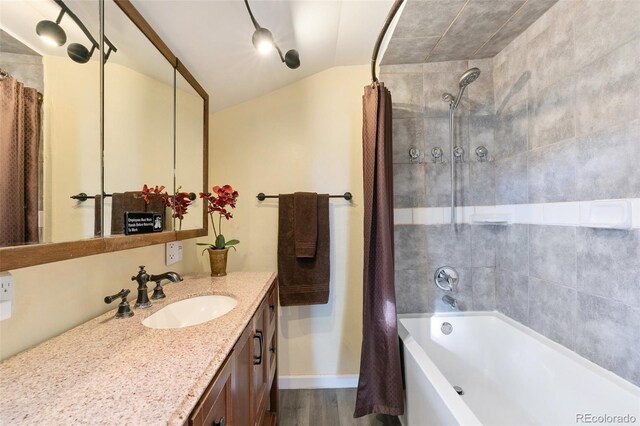 bathroom featuring vanity, hardwood / wood-style flooring, shower / tub combo with curtain, and lofted ceiling