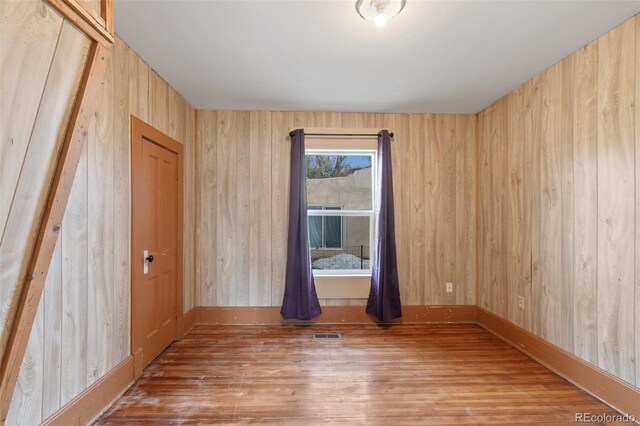 spare room featuring hardwood / wood-style floors and wooden walls