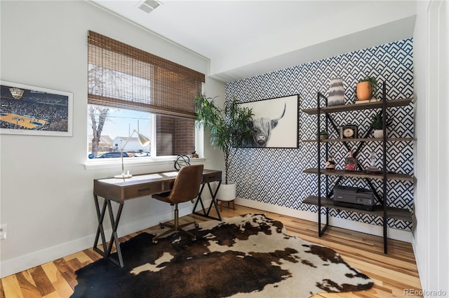 office featuring baseboards, an accent wall, visible vents, and wood finished floors