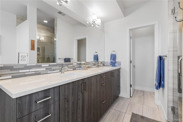 bathroom featuring tasteful backsplash, a sink, visible vents, and a shower stall