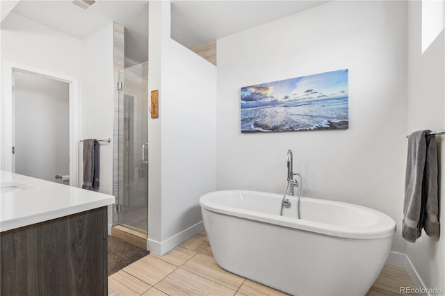 full bathroom with a freestanding tub, a shower stall, vanity, and baseboards