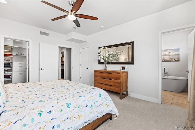 bedroom with light carpet, visible vents, a spacious closet, a closet, and ensuite bath