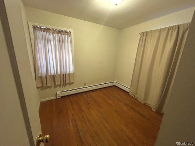 spare room with a baseboard radiator and wood-type flooring