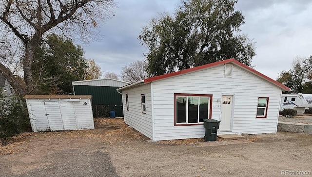 back of house featuring a storage unit