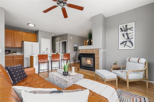 7130 Simms St Unit 206, Arvada, CO 80004 - living area featuring light wood finished floors, ceiling fan, baseboards, and a tile fireplace