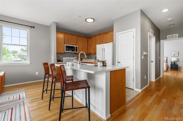 7130 Simms St Unit 206, Arvada, CO 80004 - kitchen featuring white appliances, light wood finished floors, light countertops, a sink, and a kitchen breakfast bar