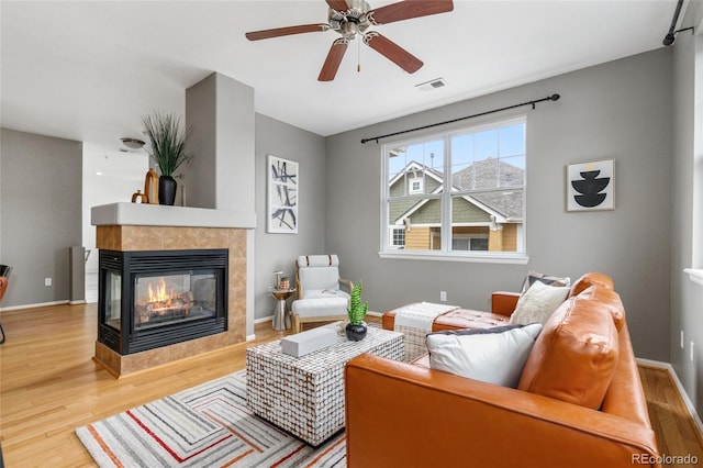 7130 Simms St Unit 206, Arvada, CO 80004 - living area with wood finished floors, a tiled fireplace, ceiling fan, and baseboards