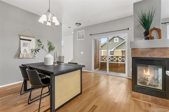 7130 Simms St Unit 206, Arvada, CO 80004 - dining space with a chandelier, light wood-type flooring, baseboards, and a tiled fireplace