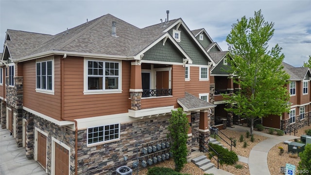 7130 Simms St Unit 206, Arvada, CO 80004 - craftsman inspired home with stone siding, a garage, a balcony, a shingled roof, and concrete driveway