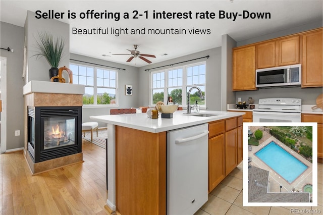 7130 Simms St Unit 206, Arvada, CO 80004 - kitchen featuring white appliances, light countertops, an island with sink, and a tiled fireplace