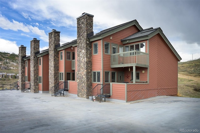 back of property with a chimney and a balcony