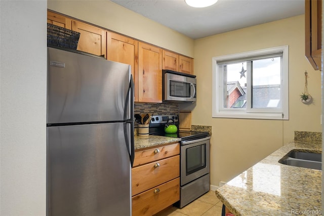 kitchen featuring appliances with stainless steel finishes, light stone counters, tasteful backsplash, and light tile patterned flooring