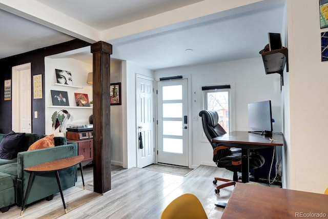 office space featuring decorative columns, beamed ceiling, and light hardwood / wood-style flooring