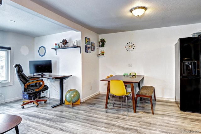 dining room with light wood-type flooring and a textured ceiling