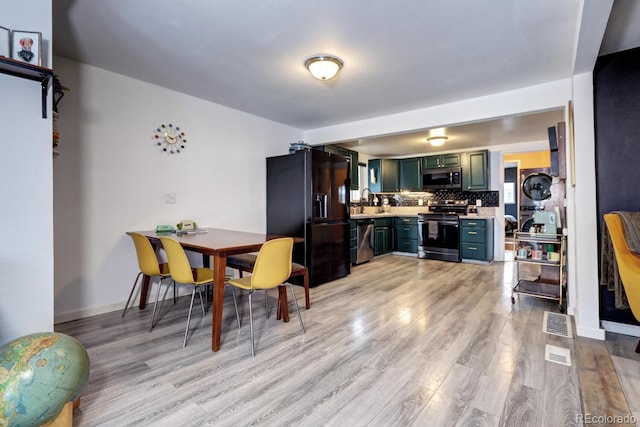 kitchen with light wood-type flooring, appliances with stainless steel finishes, sink, and decorative backsplash