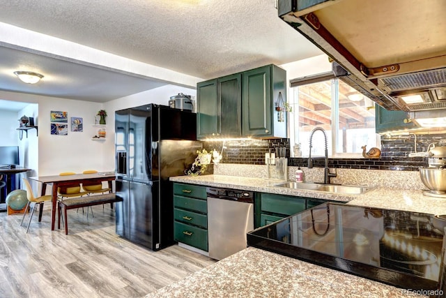 kitchen with green cabinetry, sink, stainless steel dishwasher, decorative backsplash, and black fridge