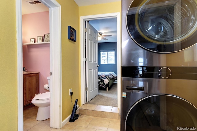 laundry room with light tile patterned flooring, ceiling fan, and stacked washing maching and dryer