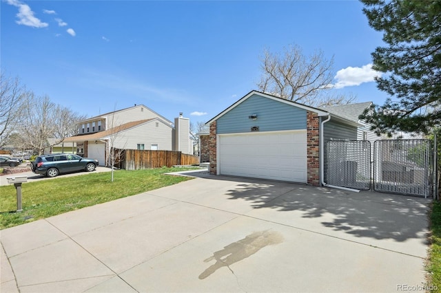 view of side of home featuring fence, an attached garage, brick siding, concrete driveway, and a yard