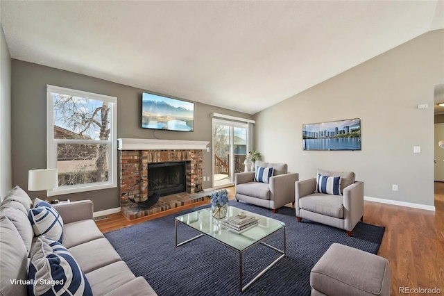 living room featuring baseboards, wood finished floors, lofted ceiling, and a fireplace