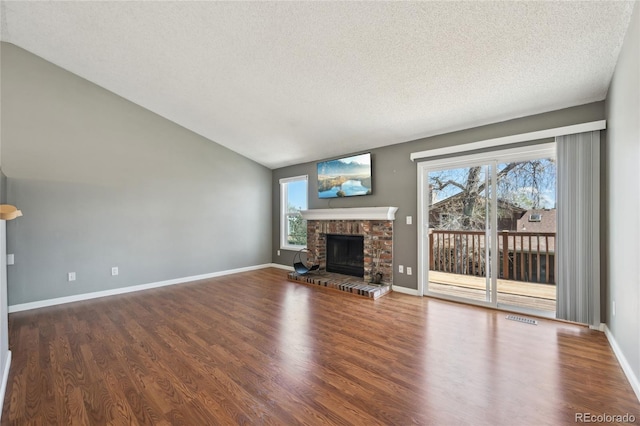 unfurnished living room featuring a fireplace, vaulted ceiling, wood finished floors, and a wealth of natural light