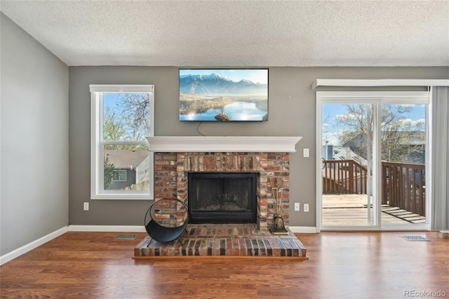 living room with a textured ceiling, a healthy amount of sunlight, wood finished floors, and a fireplace
