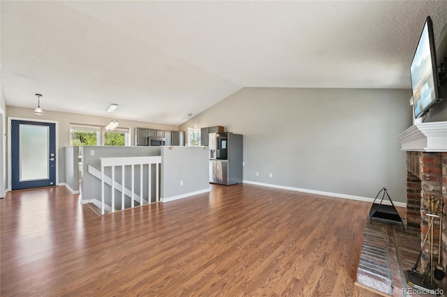 unfurnished living room with baseboards, wood finished floors, vaulted ceiling, and a fireplace