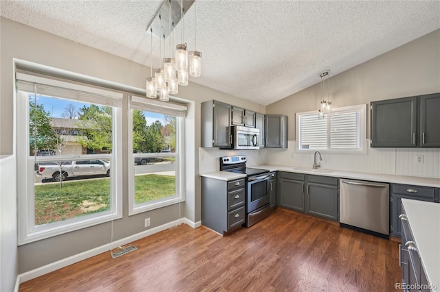 kitchen featuring a textured ceiling, a sink, appliances with stainless steel finishes, a notable chandelier, and gray cabinetry