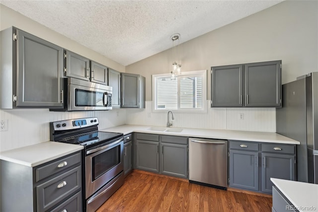 kitchen with lofted ceiling, a textured ceiling, a sink, gray cabinetry, and stainless steel appliances