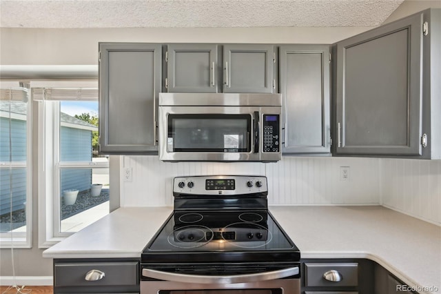 kitchen featuring light countertops, stainless steel appliances, a textured ceiling, and gray cabinetry