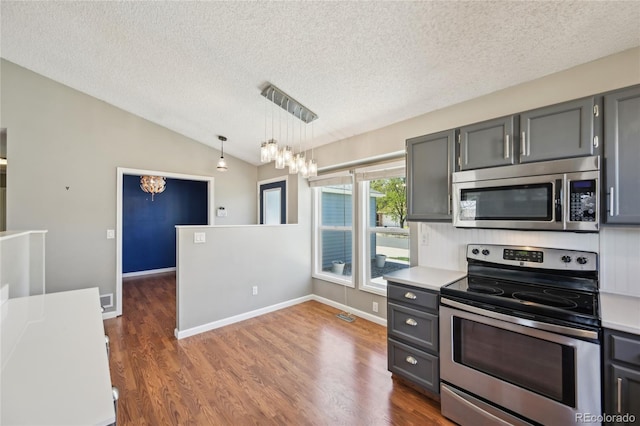 kitchen with a textured ceiling, a chandelier, light countertops, lofted ceiling, and stainless steel appliances