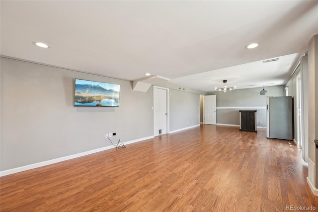 unfurnished living room featuring an inviting chandelier, light wood finished floors, recessed lighting, and visible vents
