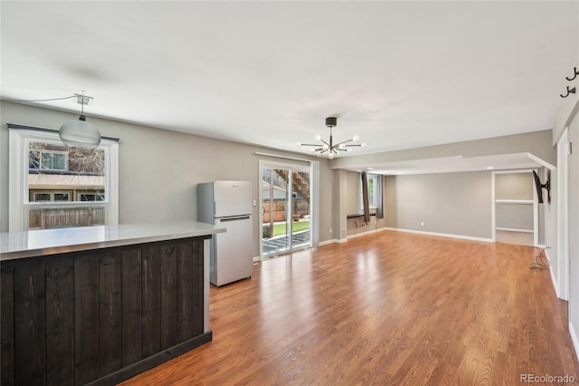kitchen with freestanding refrigerator, a chandelier, light wood-type flooring, and light countertops