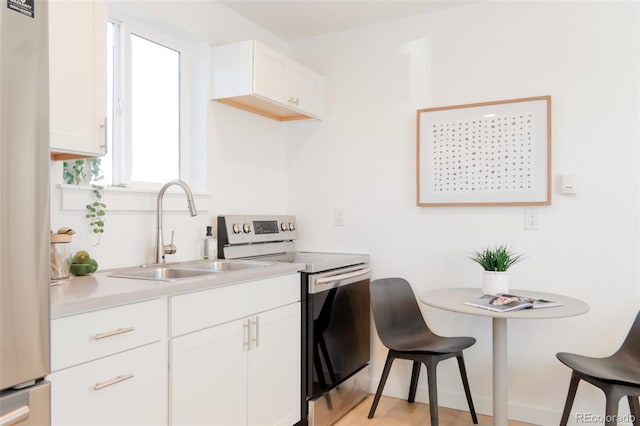 kitchen featuring light countertops, appliances with stainless steel finishes, a sink, and white cabinets