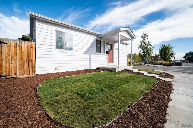 ranch-style home with a front yard and fence