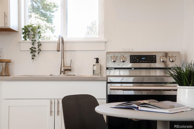 kitchen featuring light countertops, stainless steel electric range, and white cabinets