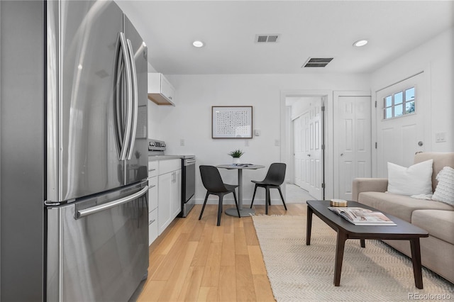 kitchen featuring stainless steel appliances, white cabinets, visible vents, and light wood-style flooring