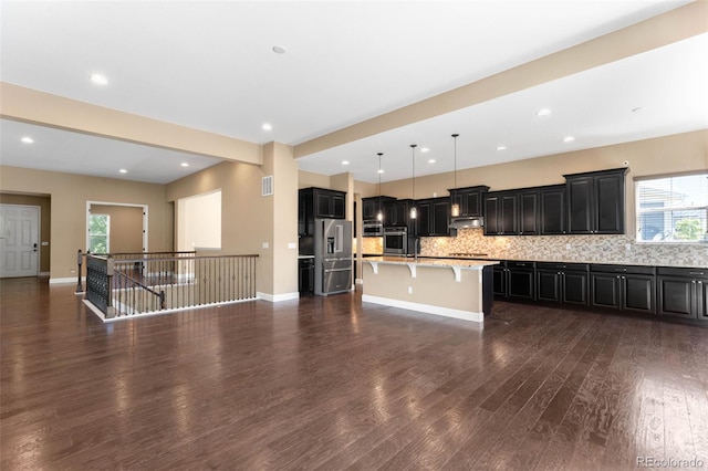 10122 Des Moines St, Parker, CO 80134 - kitchen featuring stainless steel appliances, dark cabinetry, a kitchen breakfast bar, dark wood-type flooring, and recessed lighting