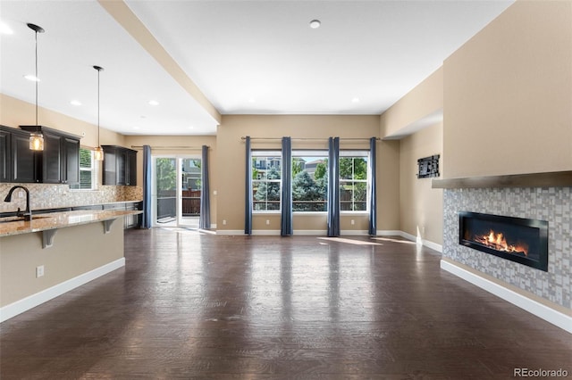 10122 Des Moines St, Parker, CO 80134 - unfurnished living room featuring a glass covered fireplace, dark wood finished floors, and recessed lighting