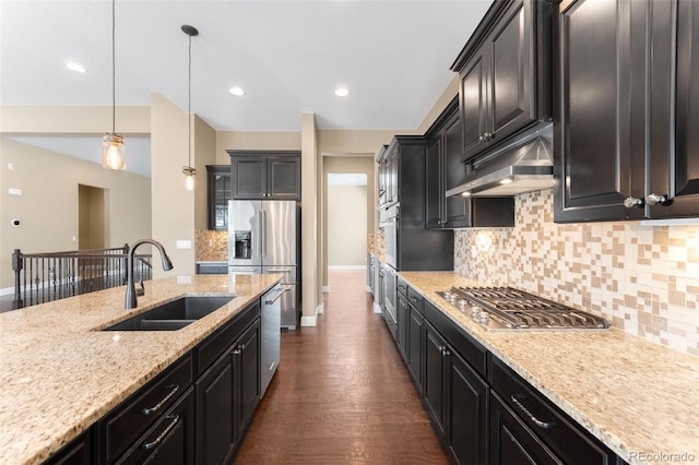 10122 Des Moines St, Parker, CO 80134 - kitchen featuring stainless steel appliances, under cabinet range hood, backsplash, dark cabinets, and dark wood-style floors