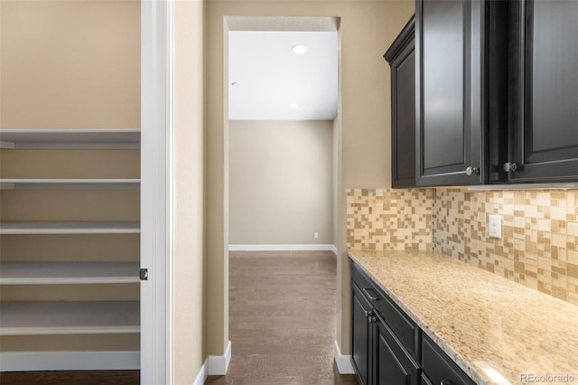 10122 Des Moines St, Parker, CO 80134 - kitchen with decorative backsplash, dark cabinets, wood finished floors, and light stone counters