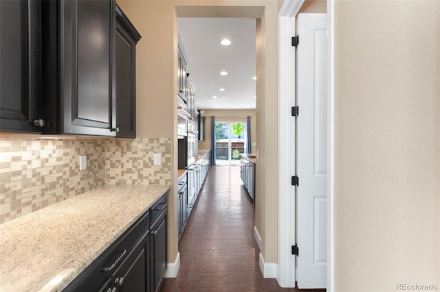 10122 Des Moines St, Parker, CO 80134 - kitchen featuring backsplash, dark cabinets, dark wood-type flooring, recessed lighting, and light stone counters