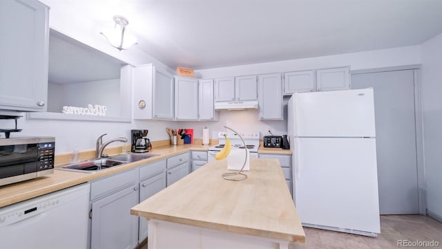 kitchen with white cabinets, white appliances, a kitchen island, and sink